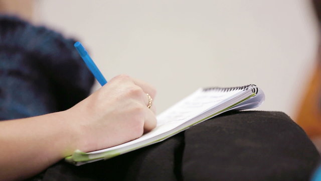 Woman holding a pen and notebook.