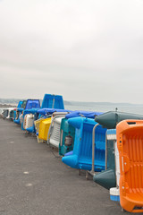 Row of colorful plastic boats on shore. Cloudy sky. Brittany. Fr