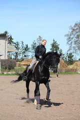 Blonde woman riding black horse