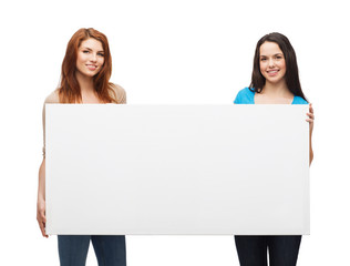 two smiling young girls with blank white board
