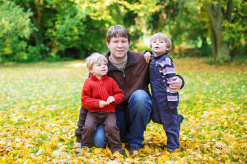 Fototapeta premium Happy dad with his little sons having fun on sunny autumn day in