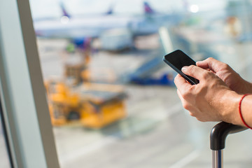 Close up man's hands using cellphone inside airport