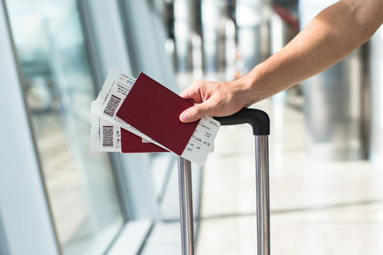 Close up of male hands holding passports and boarding pass at