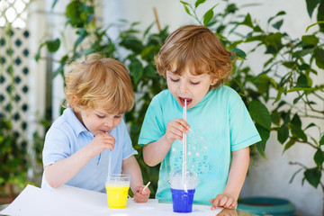 Two happy children making experiment with colorful bubbles