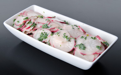 Sliced red radish with vinaigrette in a white cup