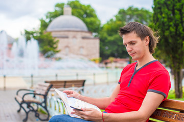 Portrait of young caucasian traveling man reading a map