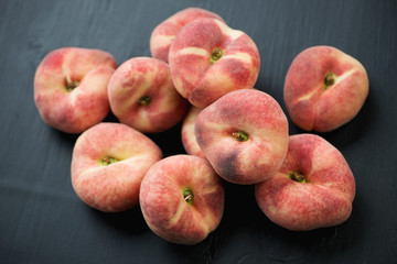 Donut peaches over black wooden surface, high angle view