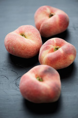 Close-up of ripe saturn peaches over black wooden background