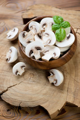 Fresh sliced champignons and green basil over wooden background