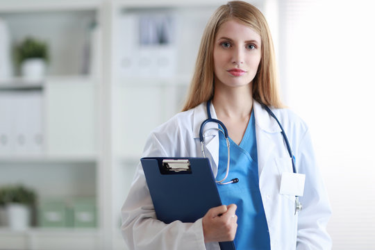 Doctor woman is standing in the near window with folder