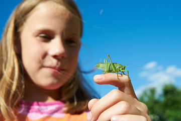 Girl with a grasshopper on a hand