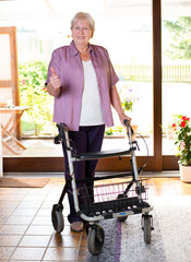 female senieor with walking frame with thumb up
