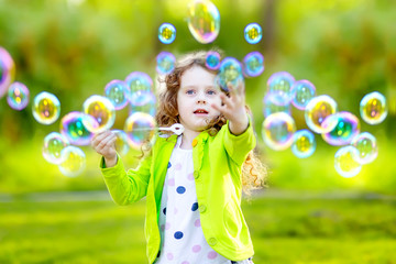 A little girl blowing soap bubbles, closeup portrait.