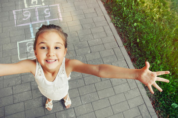 cheerful little girl playing hopscotch on playground