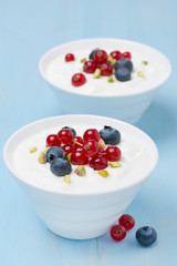 two bowls of fresh sweet yogurt with berries and pistachios