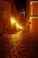 A church and cobbled street at night in Poznan .