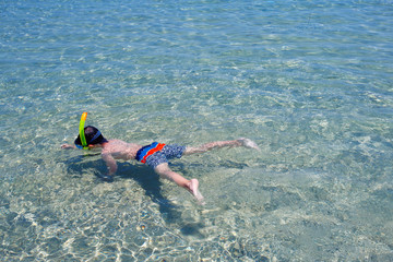 Little boy swimming in a shallow water