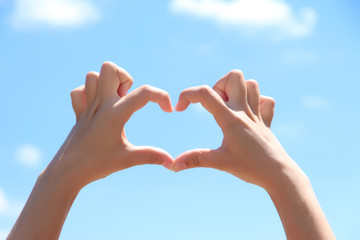 Young girl holding hands in heart shape framing