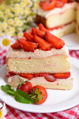 Delicious biscuit cake with strawberries on table close-up