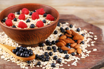 Big brown bowl with oatmeal and berries on a wooden table
