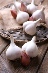 Fresh garlic on wicker mat, on wooden background