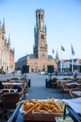 Fototapeta premium Typowy posiłek belgijski - frie; Dzwonnica w Brugii. Shallow DOF.