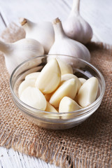 Fresh sliced garlic in glass bowl on wooden background
