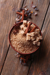 Brown sugar cubes and crystal sugar in bowl on wooden