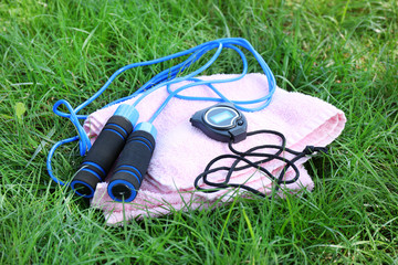 Dumbbells and bottle with water, towel on green grass