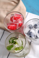 Ice cubes with mint leaves, raspberry and blueberry in glasses,