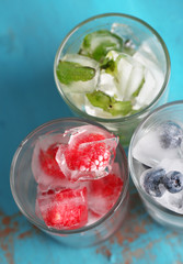 Fototapeta na wymiar Ice cubes with mint leaves, raspberry and blueberry in glasses,
