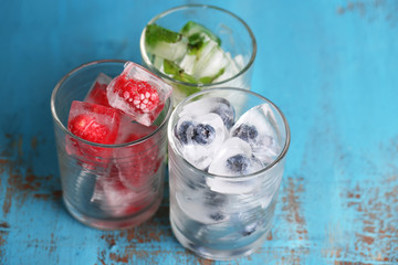 Ice cubes with mint leaves, raspberry and blueberry in glasses,