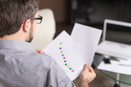 Young Man Looking At Paper In Glasses.