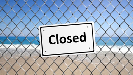 Metal fence with sign Closed in front of a beach