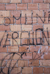 Muro di mattoni con scritte e graffiti