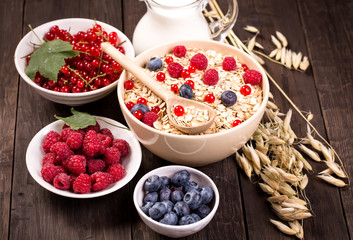 Bowls of oat flakes cereal and various berries