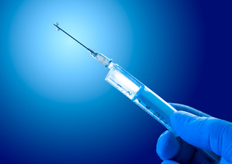 Syringe filled with vaccine on a blue background