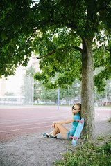beautiful girl sitting near the skateboard