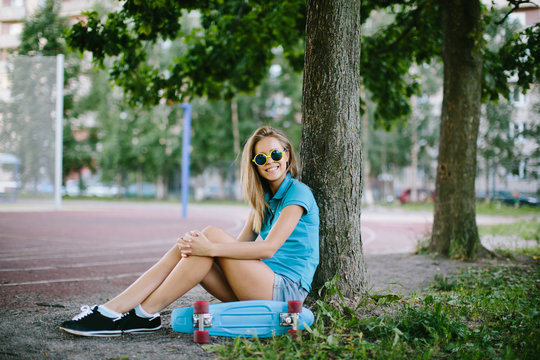 beautiful girl sitting near the skateboard