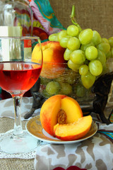 A glass of rose wine, peaches and grapes.
