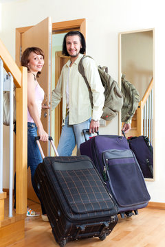 Pretty Man And Woman Together With Luggage Leaving The Home