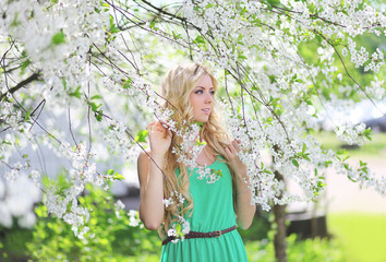 Fototapeta na wymiar Beautiful cute blonde in a spring garden looking to the side
