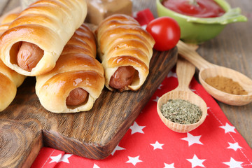 Baked sausage rolls on board on table close-up