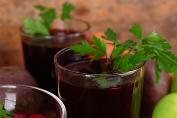 Glasses of fresh beet juice and vegetables on wooden background
