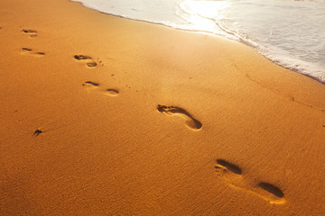 beach, wave and footsteps at sunset time
