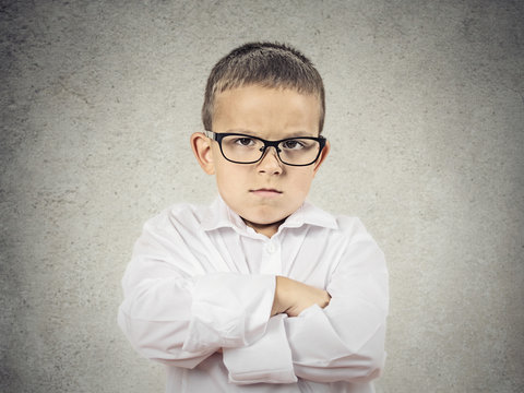 Portrait Angry, grumpy Boy with glasses on grey wall background 