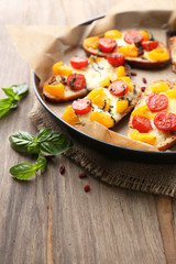 Tasty bruschetta with tomatoes on pan, on old wooden table