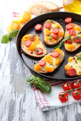 Tasty bruschetta with tomatoes on pan, on old wooden table