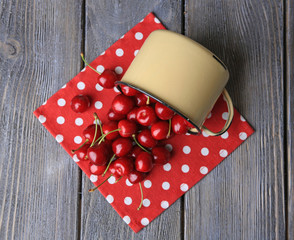 Sweet cherries in mug on wooden background