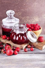 Berries jam in glass jars on table, close-up